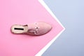 Trendy pink suede women\'s mule decorated with pearls and rhinestones on a creative geometric background with copy space.