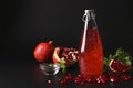 Trendy pomegranate drink with basil seeds in bottle on black background, Closeup