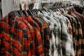 Trendy red, white, green plaid shirts hang neatly on a hanger in the store.