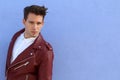 Trendy relaxed young man with a modern haircut standing against a blue background looking at the camera, three quarter pose Royalty Free Stock Photo