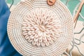 Trendy round crossbody straw bag with seashells on the beautiful lounge chair near a pool