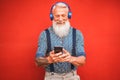 Trendy senior man using smartphone app with red backgorund - Mature fashion male having fun with new trends technology - Tech and