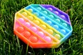 Trendy silicone colorful rainbow antistress pop it toy for baby on green grass. Top view