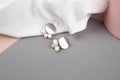 Trendy silver earrings over crumpled withe fabric background. Fashionable women& x27;s jewelry with pearls