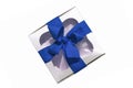 Silver metallic gift box with a blue ribbon bow isolated on white background. Copy space, mockup, flatlay, top view Royalty Free Stock Photo