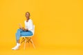 Trendy smiling African American woman sitting on a chair using tablet computer Royalty Free Stock Photo