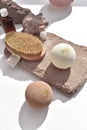 Trendy sunlight spa massage composition with bath bombs, body brush on stone stands.