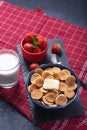 Trendy tiny cereal pancakes with slice of butter in blue bowl, strawberries, glass of milk on red background, rural Breakfast Royalty Free Stock Photo