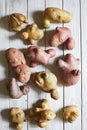 Trendy ugly potatoes on a white wooden background. The concept of ugly vegetables. View from above. Vertical image