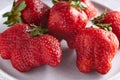 Trendy ugly strawberries in a plate on a light background