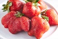 Trendy ugly strawberries in a plate on a light background