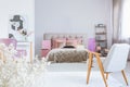 Trendy vintage armchair in bedroom interior with black and white poster and king size bed with cozy bedding Royalty Free Stock Photo