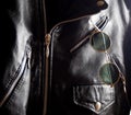 Trendy vintage circle sunglasses in a pocket of a studded jacket