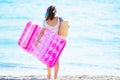 Trendy woman on beach holding inflatable mattress