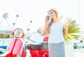 Trendy woman drinking takeaway coffee near her red moped on the Royalty Free Stock Photo