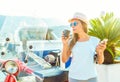 Trendy woman drinking takeaway coffee near her red moped on the Royalty Free Stock Photo