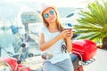 Trendy woman drinking takeaway coffee near her red moped on the Royalty Free Stock Photo