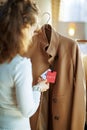 Trendy woman examines sale price tag on beige coat