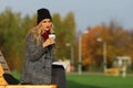 Trendy woman in stylish coat sitting on the bench in city park. Royalty Free Stock Photo