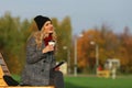 Trendy woman in stylish coat sitting on the bench in city park. Royalty Free Stock Photo