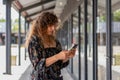 Trendy woman using her smartphone while strolling in a modern shopping district Royalty Free Stock Photo