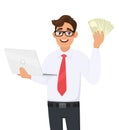 Trendy young businessman holding laptop and showing cash, money or currency notes in hand. Stylish person using computer. Royalty Free Stock Photo