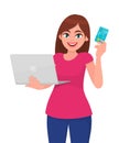 Trendy young woman holding laptop computer and showing credit, debit or ATM card. Stylish girl using digital device. Royalty Free Stock Photo