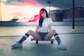 Trendy young woman sitting on skateboard in sunset Royalty Free Stock Photo