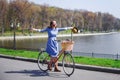 Trendy young woman stop to riding on her vintage bike with basket of flowers while focused chatting or talk on smart phone outside Royalty Free Stock Photo