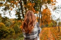 Trendy young woman in stylish autumn clothes enjoys the autumn scenery in the park. Elegant girl model in a fashionable coat in a Royalty Free Stock Photo