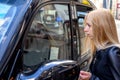 Trendy young woman talking to taxi driver in downtown London, England Royalty Free Stock Photo