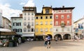 View of the colorful historic buildings surrounding Piazza Duomo, Trento, Italy. Terraces of the bars and people strolling