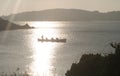 Tresco ladies rowing gig team resting on the water in reflected silvery sunlight at sunset. Off Tresco Isles of Scilly England.