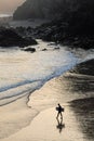 Trevaunance Cove at dawn as a lone surfer walks out to go surfing, England