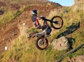 Trial motorcyclist standing on bike wheelie