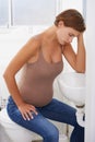 The trials of becoming a mother. A pregnant woman struggling with morning sickness in the bathroom.