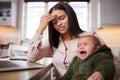 Trials and tribulations of motherhood. a young woman using a laptop while caring for her adorable baby at home.