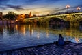 Triana bridge in Seville over the Guadalquivir river at sunset, with lights reflecting in the river water, an idyllic and charming