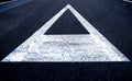 A triangle arrow direction marked in a white painted sign on a black asphalt road. Royalty Free Stock Photo