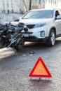 Triangle emergency sign is close to car after road accident with motorcycle