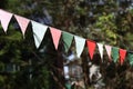 Closeup of multicolored bunting hanging up in front of a green background,triangle flag blur background