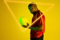 Triangle neon over african american young rugby player holding ball against yellow background