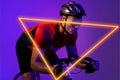 Triangle neon over confident biracial young male cyclist riding bicycle against purple background Royalty Free Stock Photo