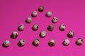 Triangle of quail eggs on a textured pink background Royalty Free Stock Photo