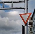 Triangle red yield or give way sign attached on a pole against a blue cloudy sky Royalty Free Stock Photo