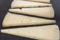 Triangle-shaped slices of aged spanish manchego cheese on a dark stone plate Royalty Free Stock Photo