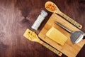 Triangular cheese and grater on a cutting Board. bamboo spatulas with paste and a salt mill on a wooden background
