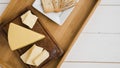 triangular cheese wedges wooden tray against white desk. High quality photo