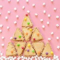 Triangular cookies are folded in shape of Christmas tree and have multi-colored round dragees on them.