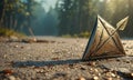 triangular metallic object lies on gravel path, surrounded by forested area and sunlight filtering through